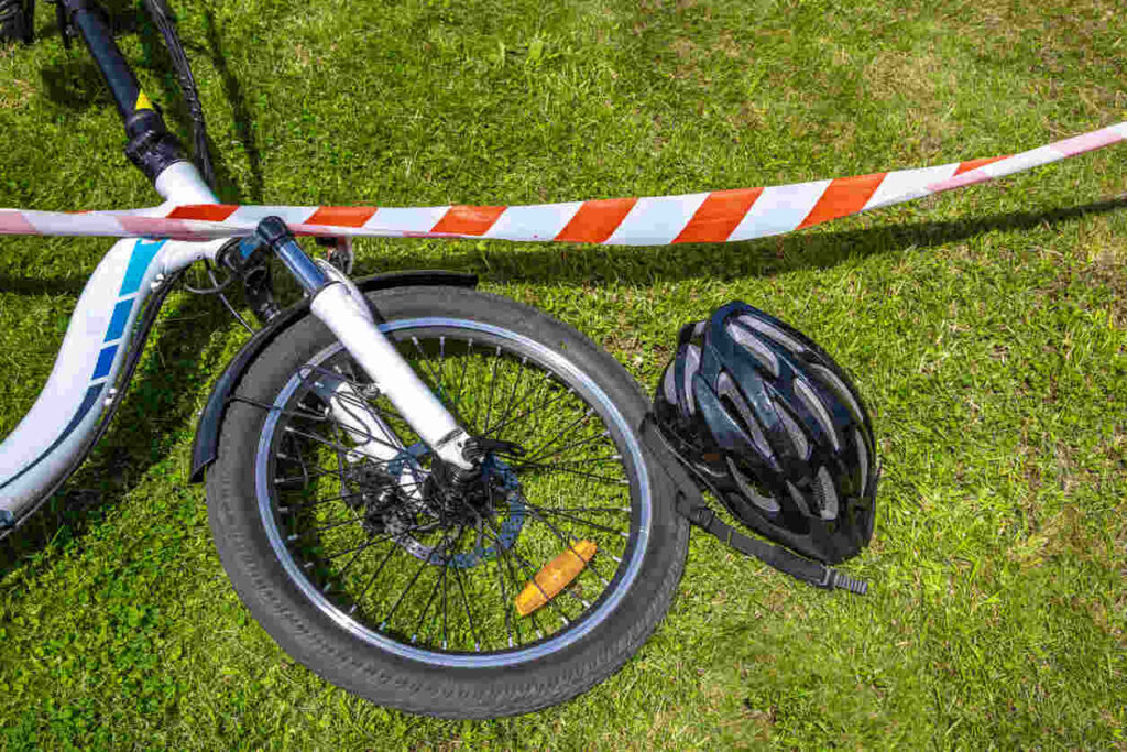 A bicycle and person's legs on the ground next to a car bumper after a hit-and-run accident in Chicago.