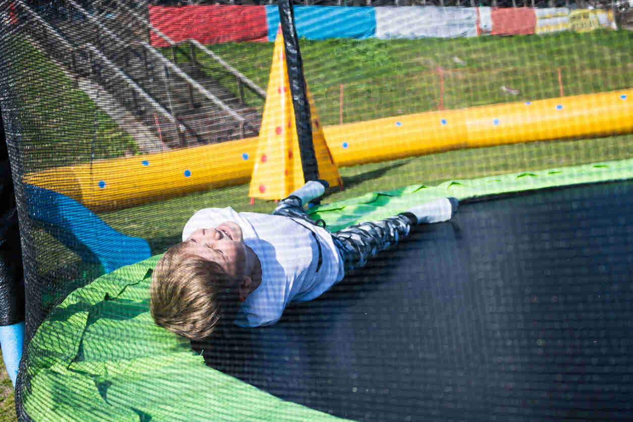 Child lying injured on a trampoline, symbolizing a trampoline accident and need for an attorney.